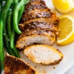 Baked Chicken Breast served with green beans and lemon wedges.