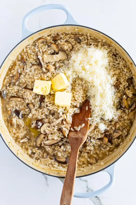 Adding butter and parmesan cheese to mushroom risotto.