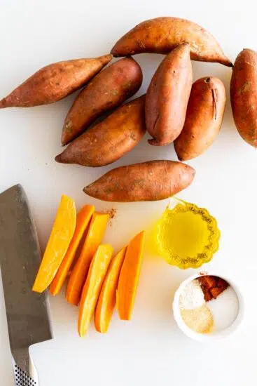 Sweet potatoes, oil and spices on cutting board