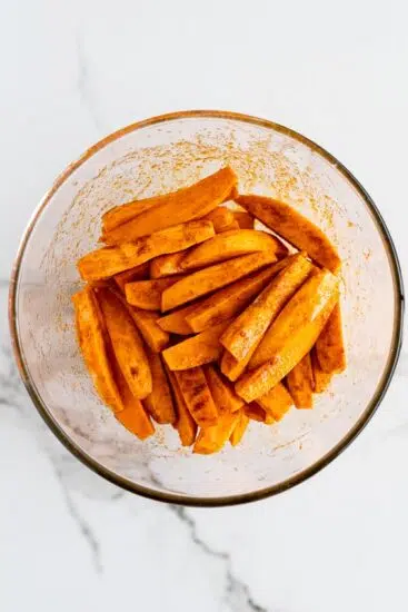 Seasoned sweet potato wedges in bowl.