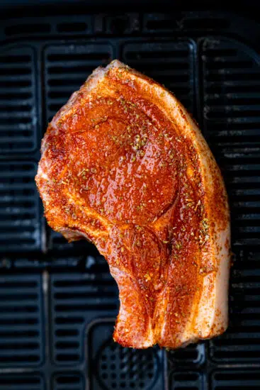 Seasoned bone-in pork chops in air fryer basket