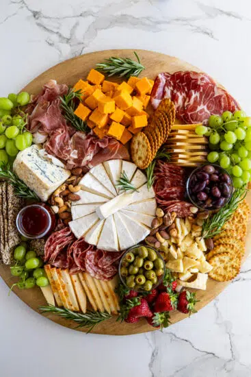 A delicious cheese board stacked with cheese, fruit and meats.
