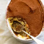 Tiramisu in oval dish with spoon.