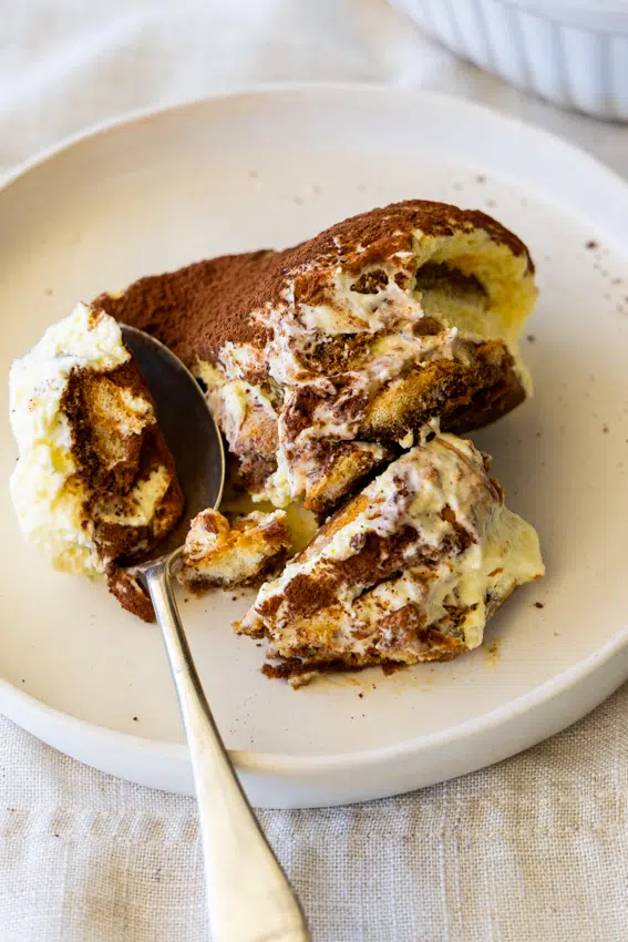 Tiramisu on serving plate with spoon.