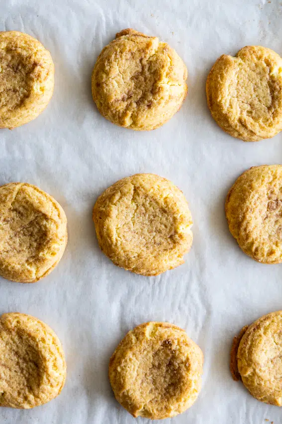 Baked snickerdoodle cookies on a cookie sheet.