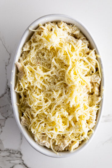 Chicken Alfredo topped with mozzarella cheese in baking dish.
