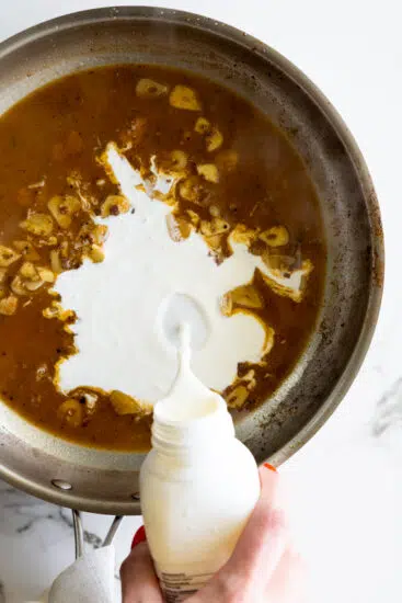 Heavy cream poured into pan with chicken livers
