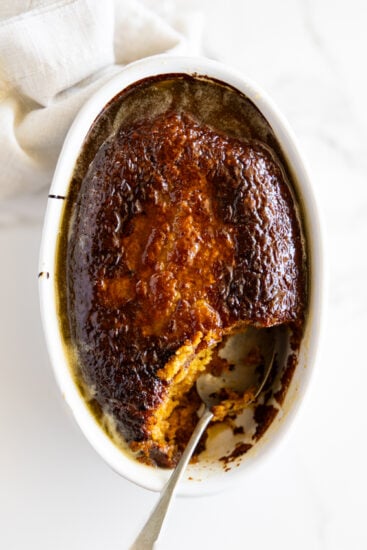 Baked malva pudding with syrup and serving spoon.