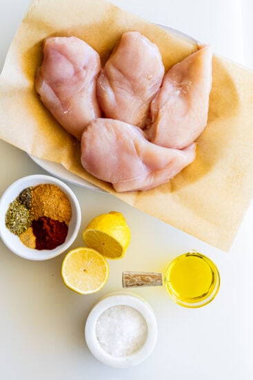 Ingredients for air fryer chicken breast on a white surface.