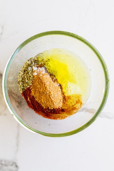 Spices, olive oil and lemon juice in a glass bowl.