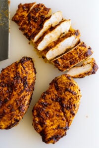 Sliced Air Fryer Chicken Breast on a white cutting board.