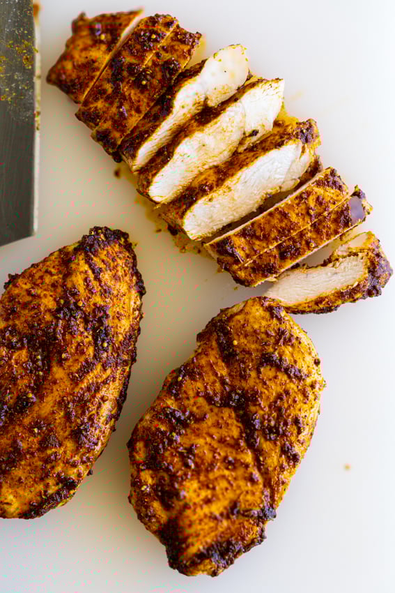 Sliced Air Fryer Chicken Breast on a white cutting board.