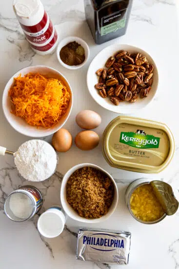Ingredients for carrot cake on a white surface.