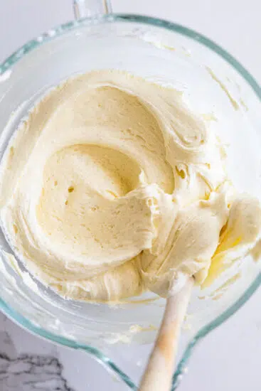 Vanilla bean cream cheese frosting in mixing bowl with spatula.