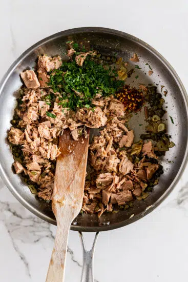 Canned tuna, herbs and aromatics in a pan.