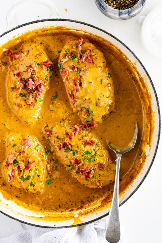 Easy Smothered chicken in savory gravy topped with bacon bits in a large pan.