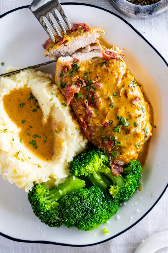 Smothered chicken served with mashed potatoes and broccoli.