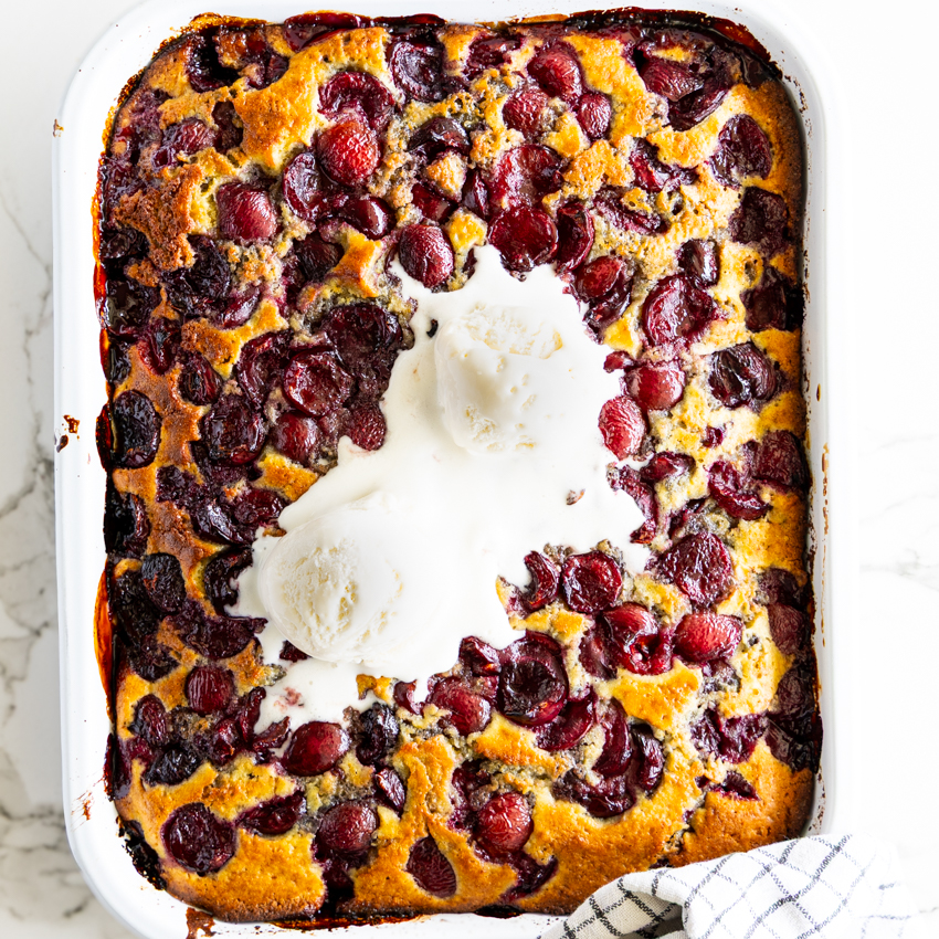 Cherry Cobbler with vanilla ice cream in a baking dish.