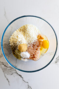 Ingredients for chicken meatballs in a glass bowl.