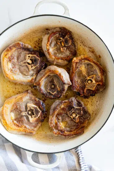 Seared lamb neck in deep braiser.