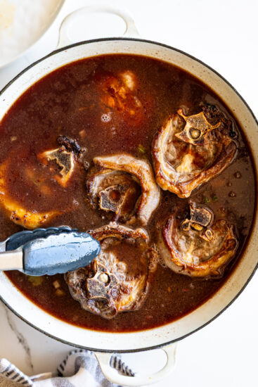 Seared lamb necks placed into red wine and stock to braise.
