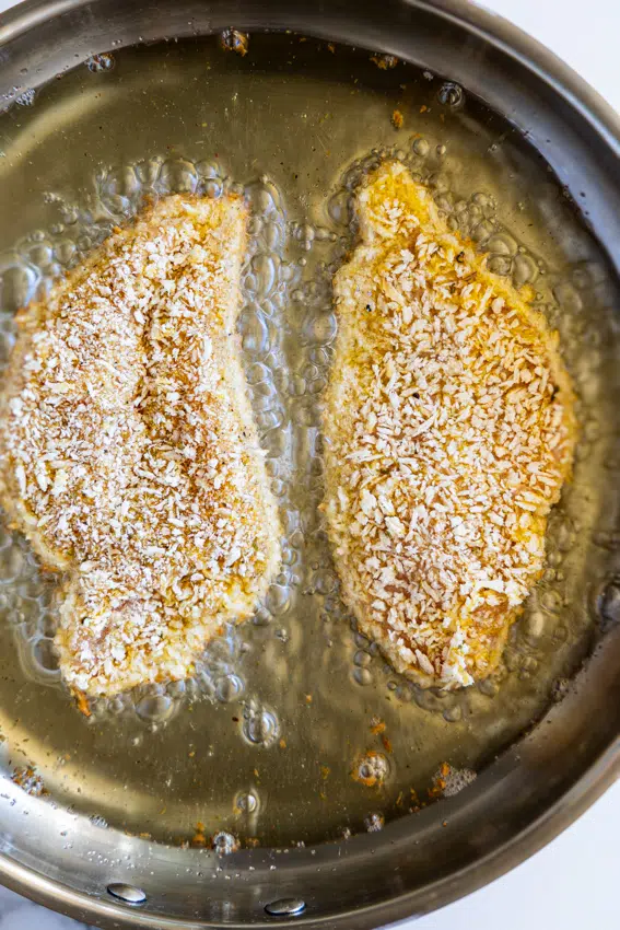 Breaded chicken cutlets frying in hot oil.