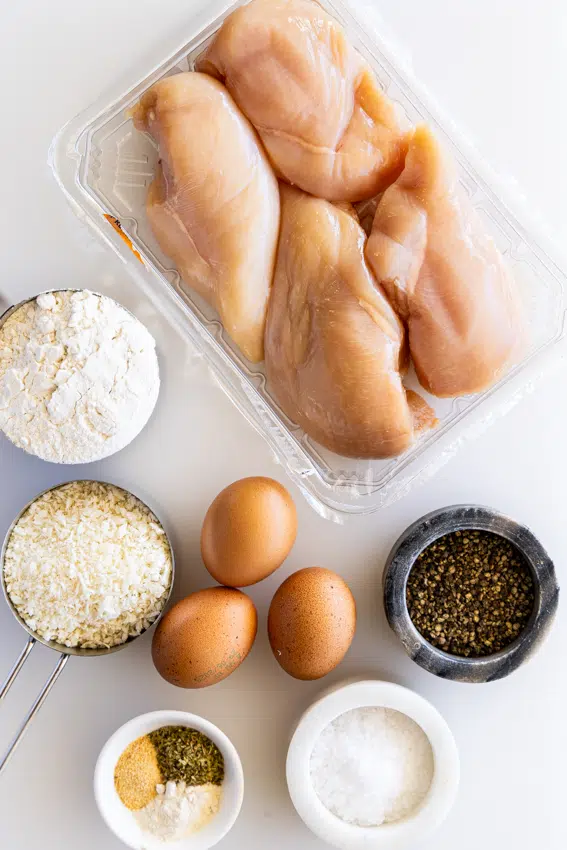 Ingredients for breaded chicken cutlets on work surface.