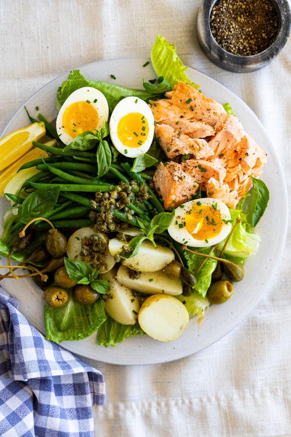 Salmon Niçoise Salad served in light blue plate on table.