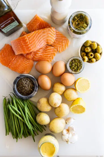 Ingredients for Salmon Niçoise Salad on a white surface.