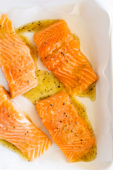 Salmon seasoned in a white baking dish.