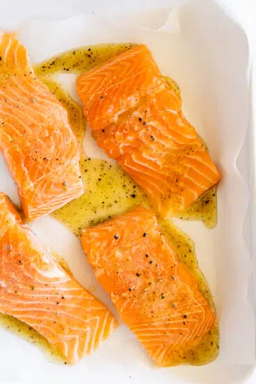 Salmon seasoned in a white baking dish.