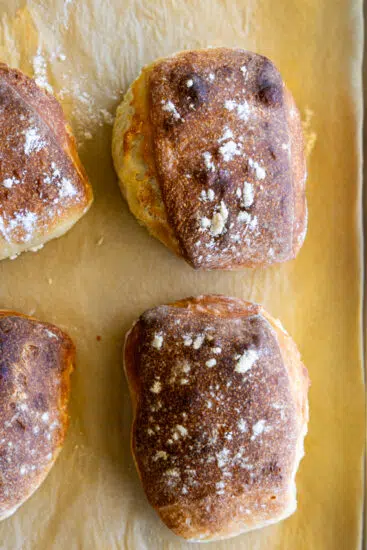 Fresh focaccia rolls on a baking sheet.