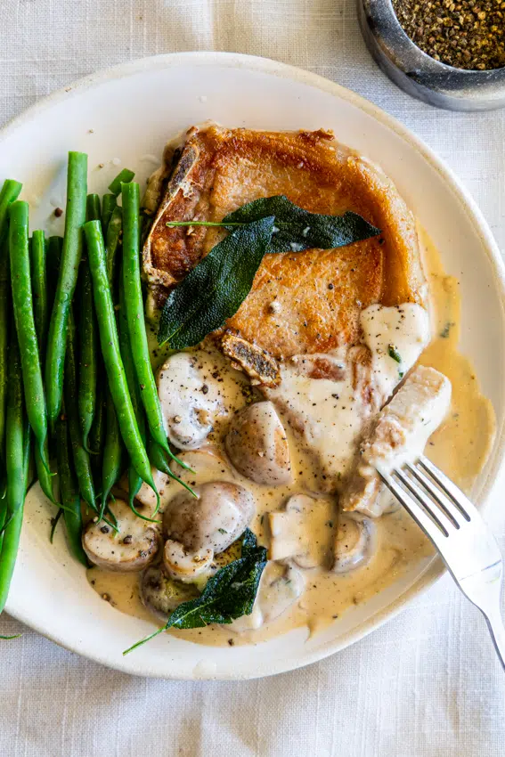 Seared pork chops with creamy mushrooms sauce served with green beans.