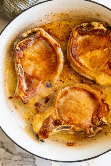 Seared pork chops in large skillet.