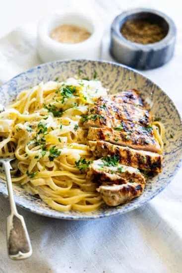 Grilled Chicken Alfredo in pasta bowl with fork.