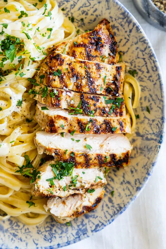 Juicy grilled chicken on fettuccine Alfredo.