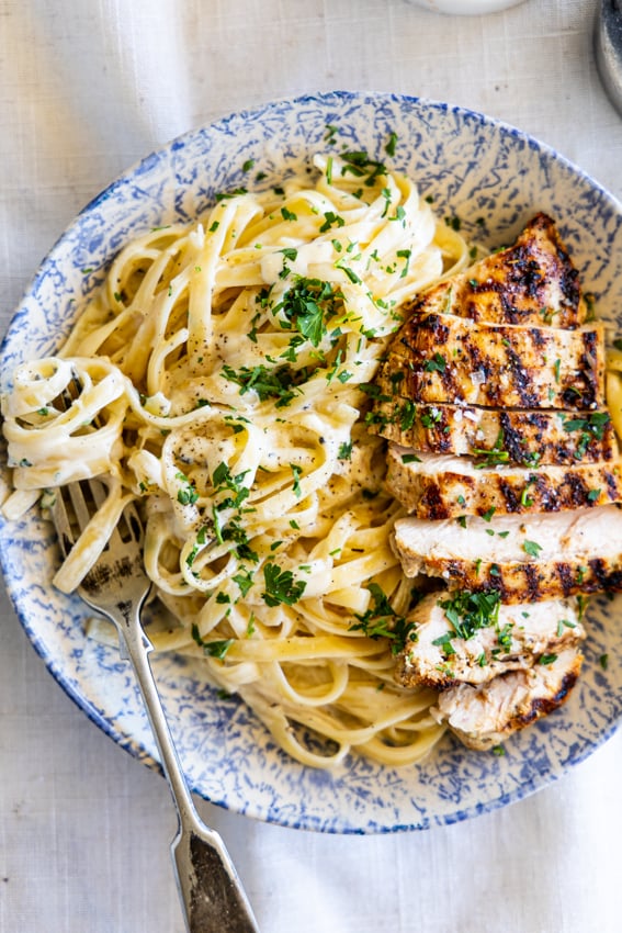 Grilled Chicken Alfredo in a pasta bowl with fork.