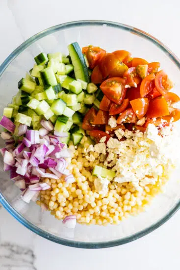 Ingredients for Pearl Couscous Salad in a glass bowl.