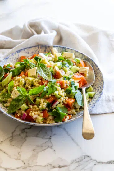 Pearl Couscous Salad in a serving bowl on marble surface.