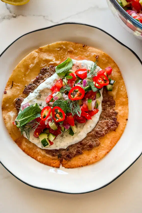 Easy Smashed Lamb Wraps with chopped salad, yogurt sauce and fresh herbs.