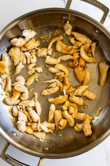 Stir fried chicken in pan.