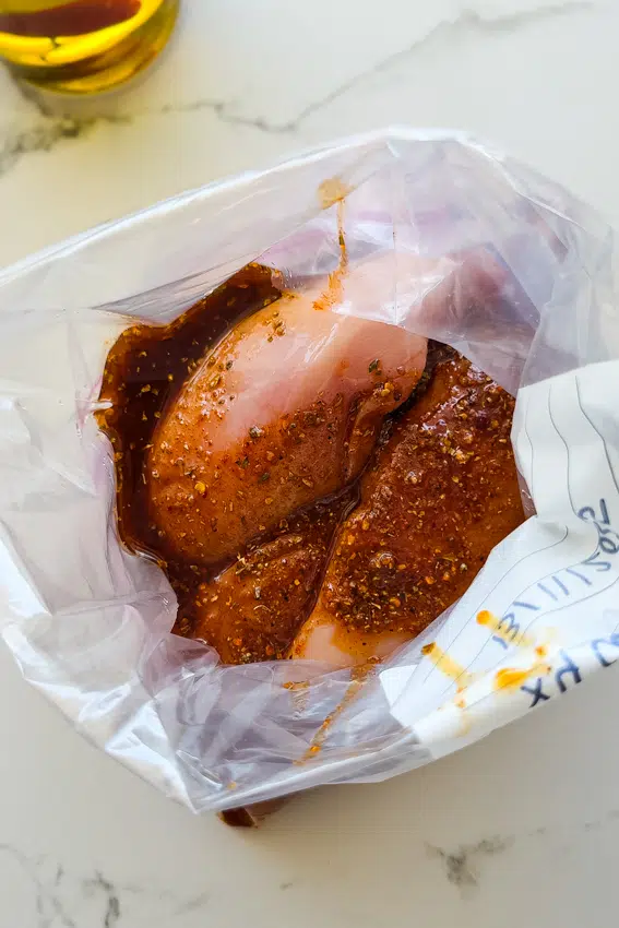 Chicken breasts marinated in a freezer bag.
