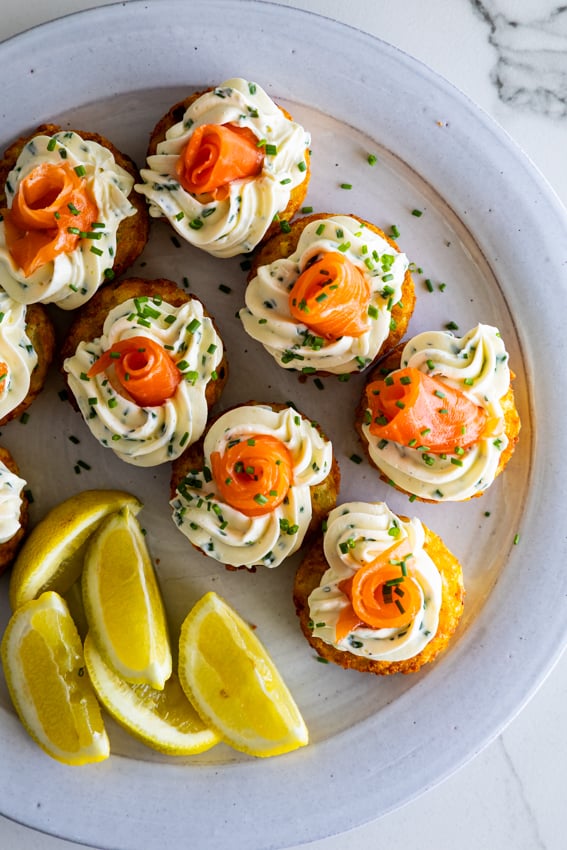 Elegant smoked salmon hashbrown bites on blue serving platter.