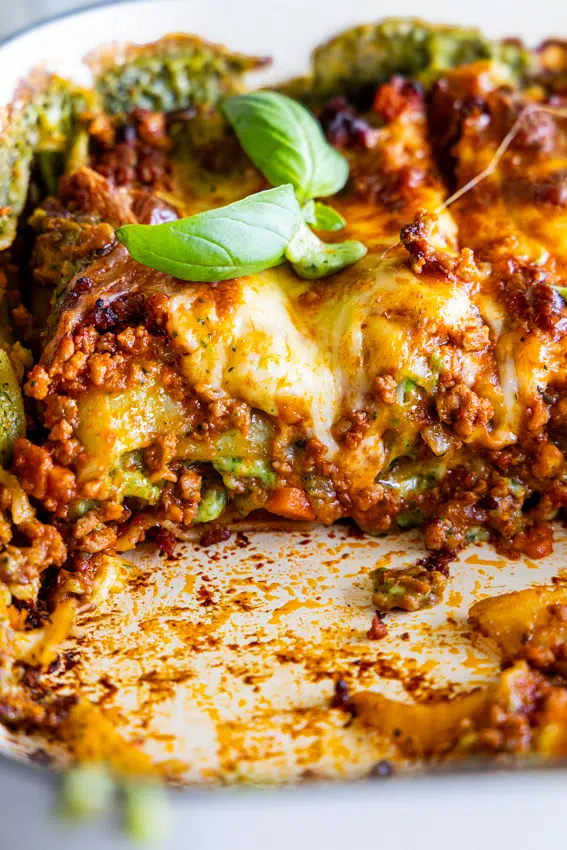 Close up of Christmas lasagna layers with mozzarella and fresh basil.