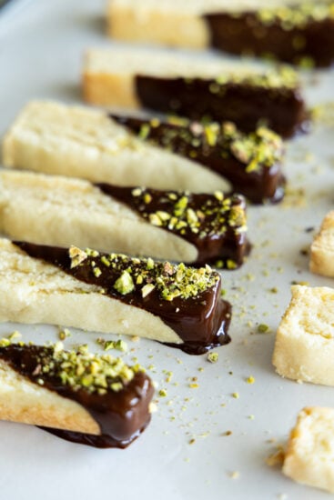 Shortbread cookie sticks dipped in dark chocolate and sprinkled with chopped pistachios.