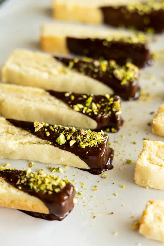 Shortbread cookie sticks dipped in dark chocolate and sprinkled with chopped pistachios.