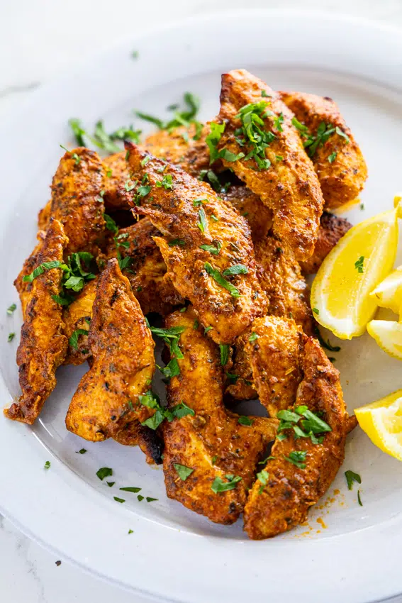 Golden brown air-fried chicken tenders on white plate.