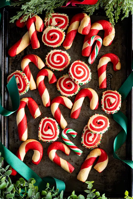 Festive Pinwheel Cookies and candy cane cookies on a baking sheet.