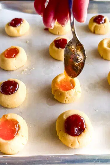Close up of buttery thumbprint cookie filled with jam.