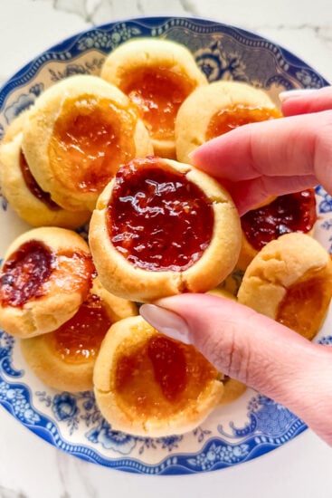 Close up of buttery thumbprint cookie showing jam-filled center.